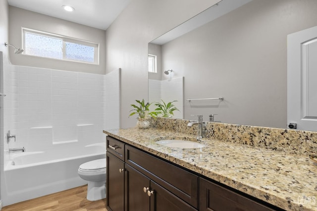 bathroom with wood finished floors, toilet, vanity, and bathing tub / shower combination