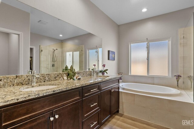 full bath featuring a bath, a shower stall, double vanity, and a sink