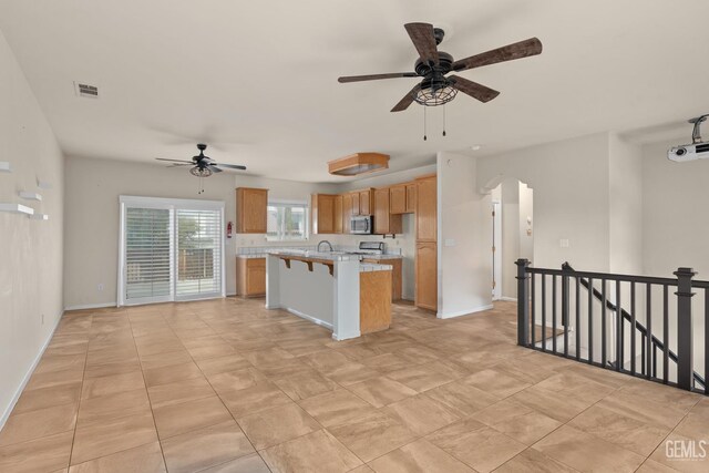 408 Brite Meadow Ct, Bakersfield, CA 93308 - kitchen with ceiling fan, stainless steel microwave, light countertops, a kitchen island, and arched walkways