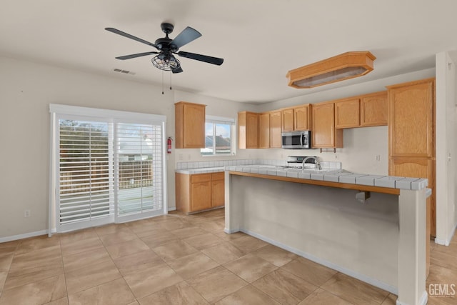 408 Brite Meadow Ct, Bakersfield, CA 93308 - kitchen with stainless steel microwave, a ceiling fan, a sink, stove, and a center island with sink