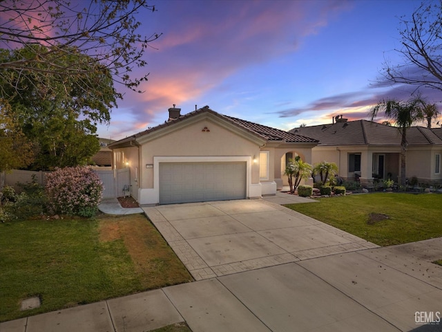 mediterranean / spanish home featuring a yard, an attached garage, fence, stucco siding, and driveway