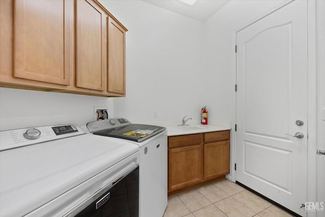 laundry room with cabinet space, light tile patterned floors, washing machine and dryer, and a sink