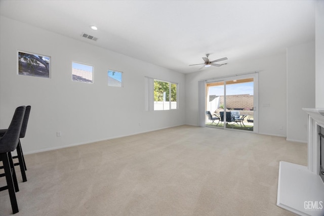 living area featuring baseboards, visible vents, light colored carpet, and a ceiling fan