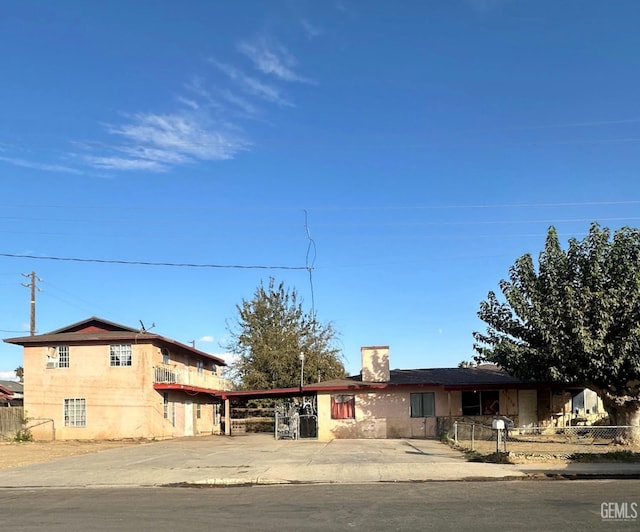 view of front of house featuring stucco siding, driveway, a fenced front yard, and a chimney