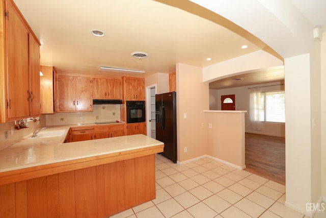 kitchen with kitchen peninsula, sink, light tile patterned flooring, and black appliances