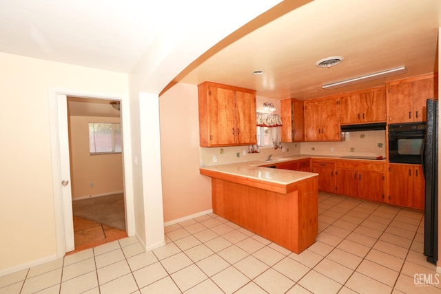 kitchen featuring kitchen peninsula, sink, light tile patterned flooring, and black appliances