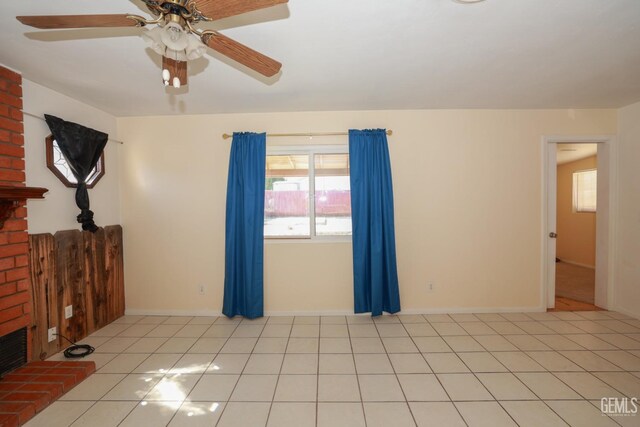 unfurnished living room featuring ceiling fan, light tile patterned floors, and a brick fireplace