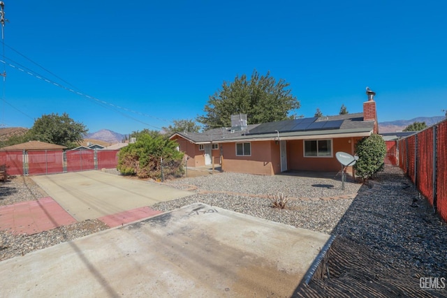 rear view of property with a mountain view and solar panels