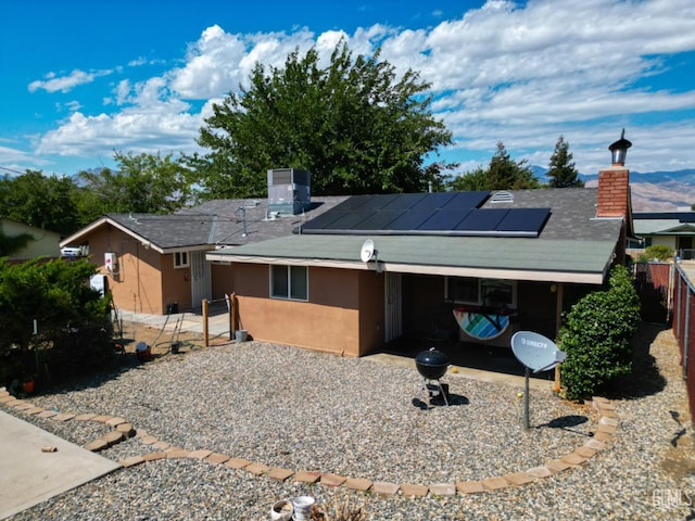 single story home with a carport, solar panels, and cooling unit