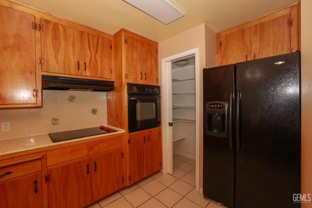 kitchen featuring black appliances, light tile patterned flooring, and backsplash