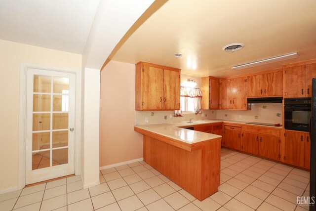 kitchen featuring kitchen peninsula, light tile patterned floors, sink, and black appliances