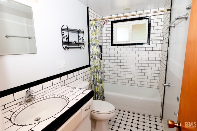 full bathroom with tile patterned floors, vanity, shower / bath combo with shower curtain, tile walls, and toilet