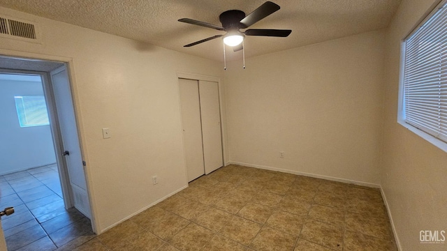 unfurnished bedroom featuring baseboards, visible vents, ceiling fan, a textured ceiling, and a closet