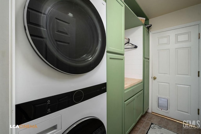 laundry area with cabinet space, dark tile patterned floors, and stacked washing maching and dryer