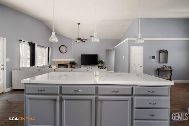 kitchen featuring open floor plan, gray cabinetry, a fireplace, and vaulted ceiling