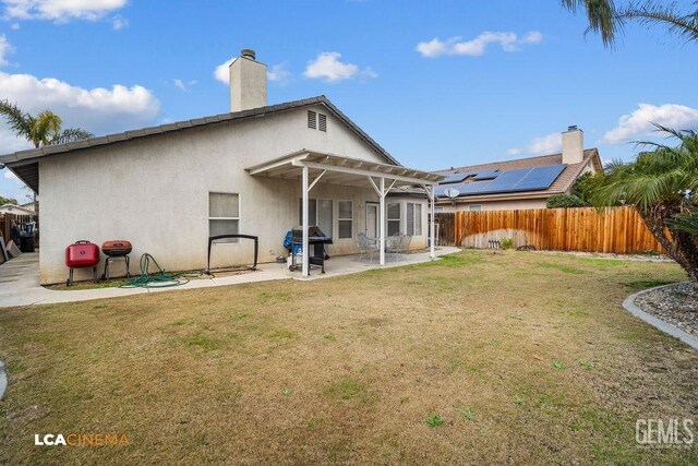 back of property featuring fence, stucco siding, a chimney, a yard, and a patio