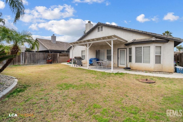 rear view of property featuring a patio, a lawn, fence, and stucco siding