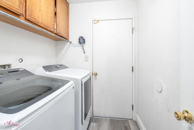 laundry room featuring cabinets, washing machine and dryer, and hardwood / wood-style floors