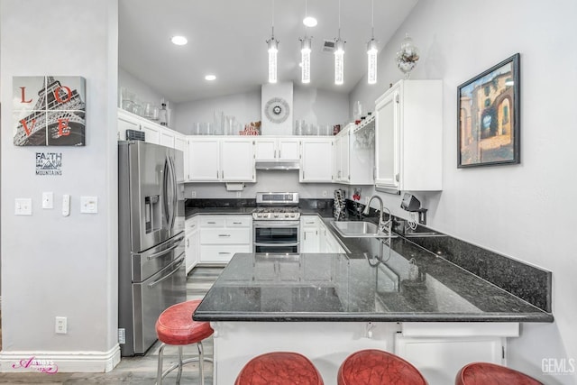 kitchen featuring appliances with stainless steel finishes, a kitchen bar, kitchen peninsula, and sink