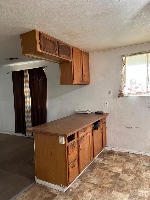 kitchen with light colored carpet, white range with gas cooktop, kitchen peninsula, and a textured ceiling