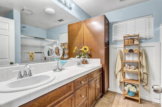 12503 Maclure Dr, Bakersfield, CA 93311 - full bath featuring double vanity, an enclosed shower, tile patterned floors, and a wainscoted wall