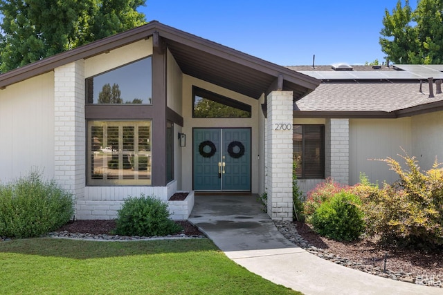 2700 Hoad Ln, Bakersfield, CA 93309 - property entrance with brick siding, a shingled roof, solar panels, and a yard