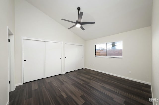 unfurnished bedroom with high vaulted ceiling, dark wood-type flooring, a ceiling fan, baseboards, and multiple closets