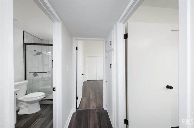 full bathroom with a baseboard heating unit, a shower stall, toilet, and wood finished floors