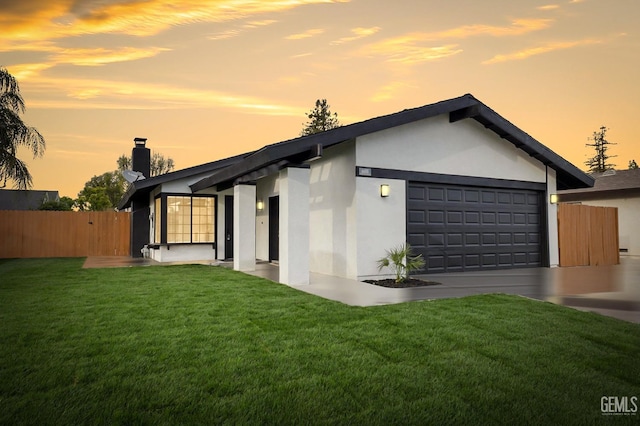 exterior space with a chimney, an attached garage, fence, a front yard, and stucco siding