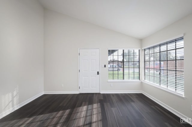 empty room with dark wood finished floors, vaulted ceiling, and baseboards