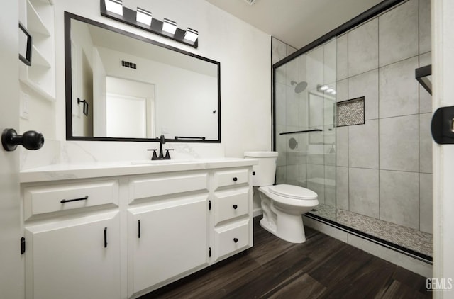 full bath featuring toilet, wood finished floors, visible vents, vanity, and a shower stall