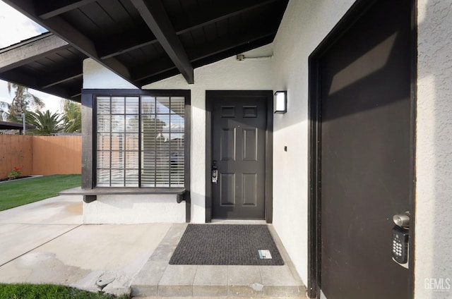 doorway to property with fence and stucco siding