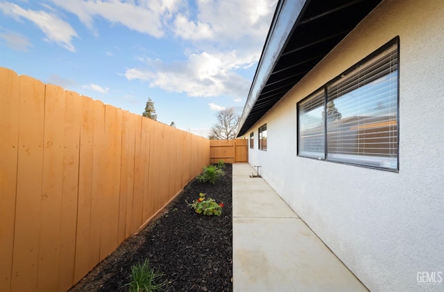 view of side of property with a fenced backyard and stucco siding