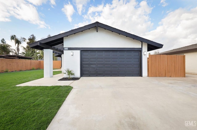 view of front of home with a garage, fence, driveway, stucco siding, and a front yard