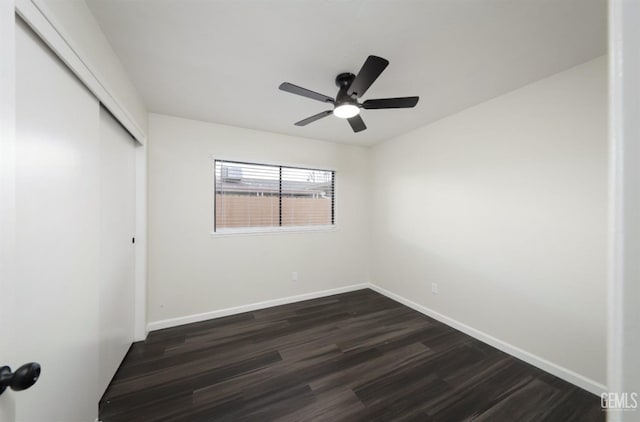 empty room featuring ceiling fan, dark wood-style flooring, and baseboards