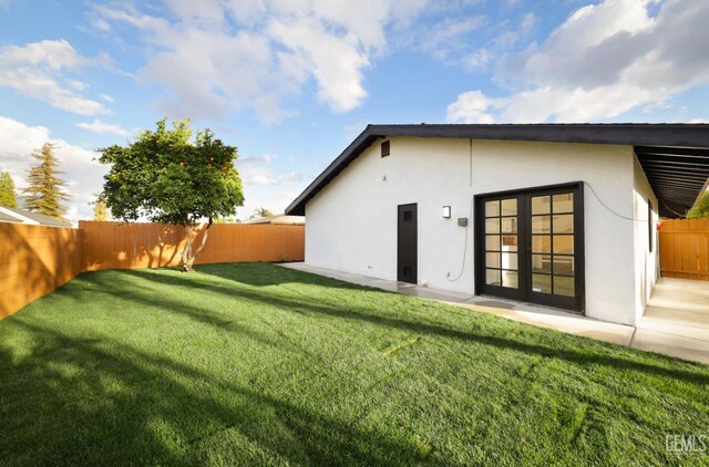 rear view of house featuring a yard, a patio area, a fenced backyard, and stucco siding