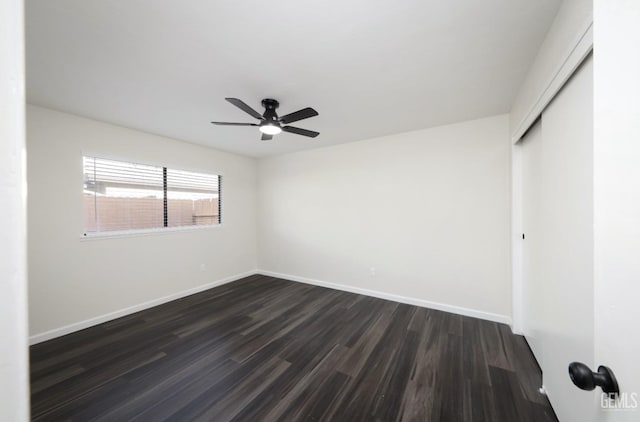 empty room featuring baseboards, dark wood finished floors, and a ceiling fan