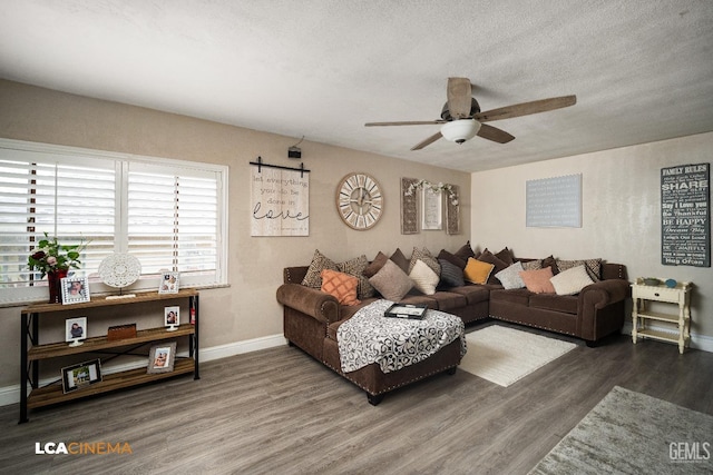 living area featuring a ceiling fan, wood finished floors, baseboards, and a textured ceiling