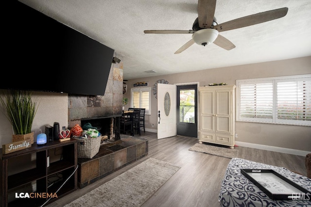 interior space with wood finished floors, a fireplace, baseboards, and a textured ceiling