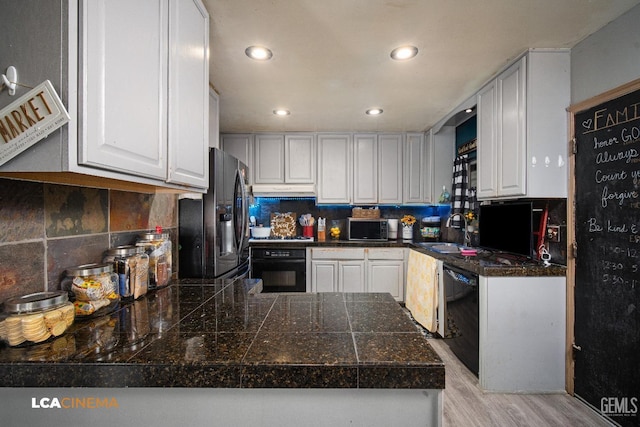 kitchen featuring tile countertops, a sink, black appliances, white cabinets, and light wood-type flooring