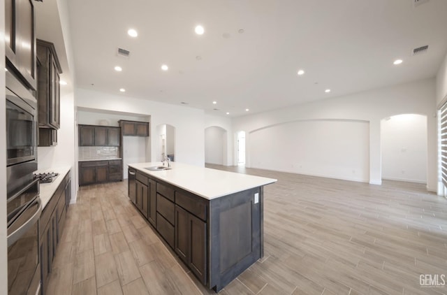 4414 Coal Rock Ct, Bakersfield, CA 93313 - kitchen featuring arched walkways, appliances with stainless steel finishes, a sink, light wood finished floors, and open floor plan