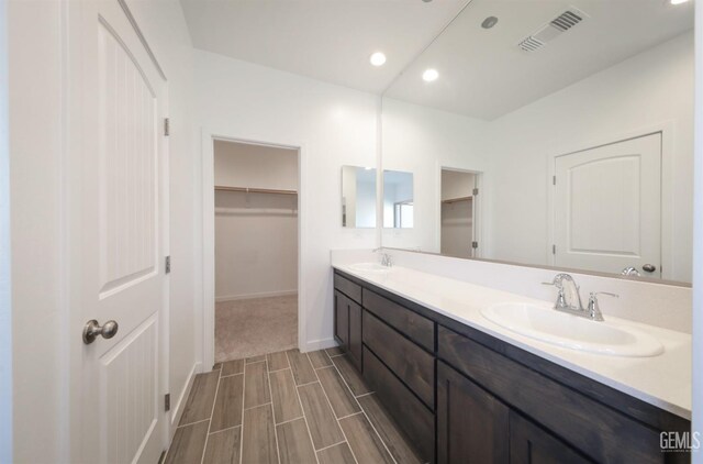 4414 Coal Rock Ct, Bakersfield, CA 93313 - bathroom featuring double vanity, a spacious closet, baseboards, recessed lighting, and wood finished floors