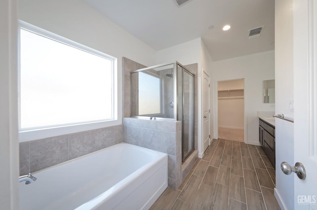 4414 Coal Rock Ct, Bakersfield, CA 93313 - full bath with a stall shower, a bath, a walk in closet, vanity, and wood finish floors