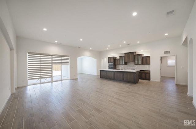 4414 Coal Rock Ct, Bakersfield, CA 93313 - unfurnished living room featuring arched walkways, baseboards, light wood-style floors, and recessed lighting