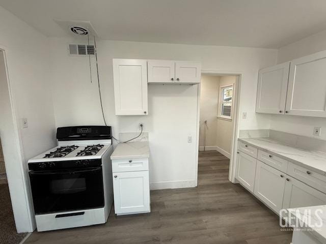 kitchen featuring white gas stove, dark hardwood / wood-style flooring, light stone counters, and white cabinetry