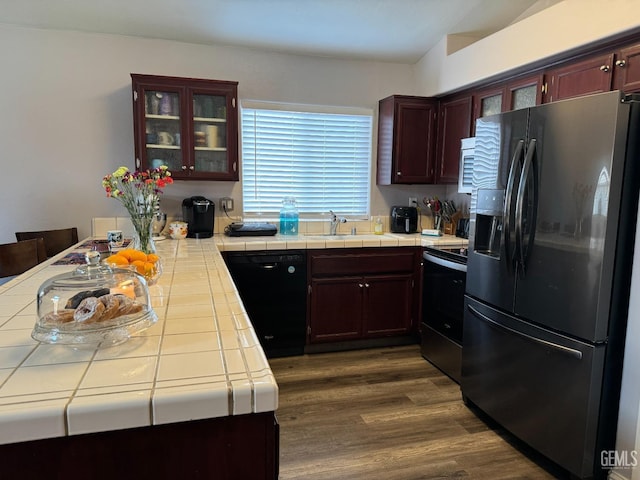 kitchen featuring black appliances, dark wood-type flooring, sink, and tile countertops