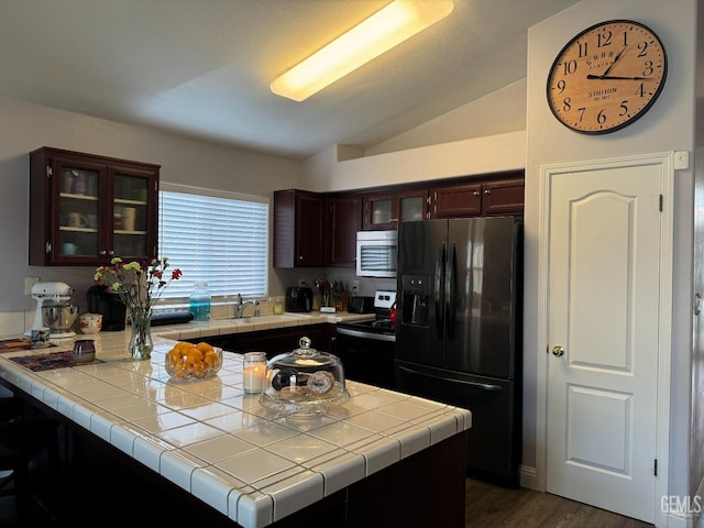 kitchen featuring dark hardwood / wood-style flooring, vaulted ceiling, refrigerator with ice dispenser, tile counters, and range with electric stovetop