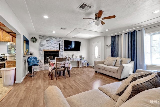 1504 Stockton Ave, Bakersfield, CA 93308 - living room featuring ceiling fan, light wood-style floors, a stone fireplace, recessed lighting, and a textured ceiling