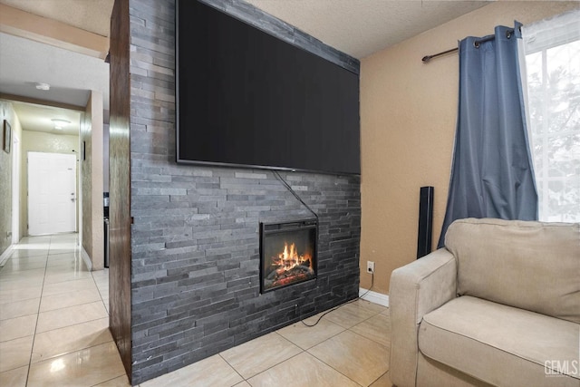 living area featuring light tile patterned floors, a textured ceiling, a fireplace, and baseboards