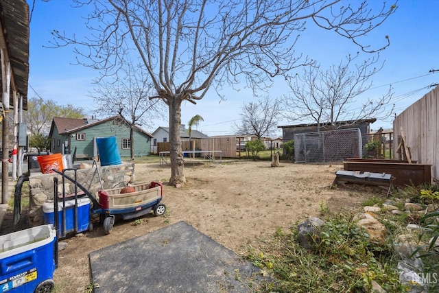 view of yard featuring a trampoline, fence, and a vegetable garden